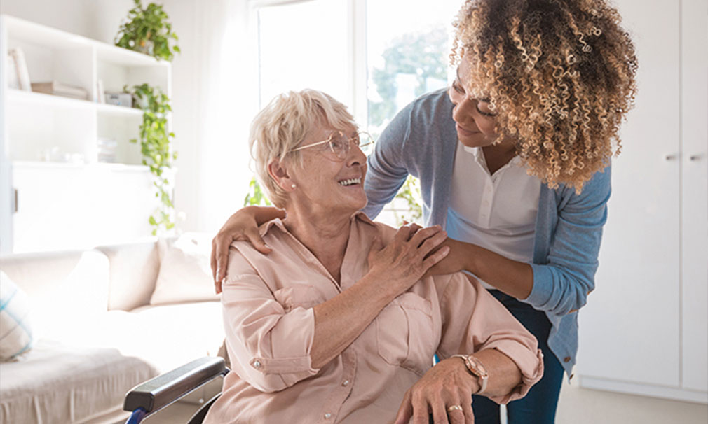 Elderly woman wearing a pink shirt ad glasses speaking to a healthcare provider.