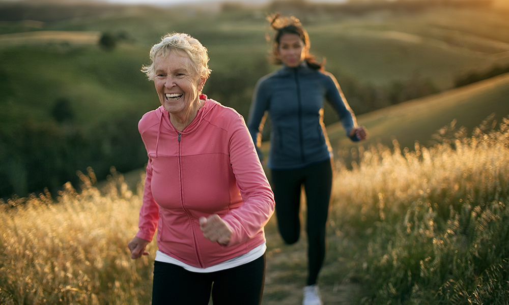 Two women smiling while running outside.