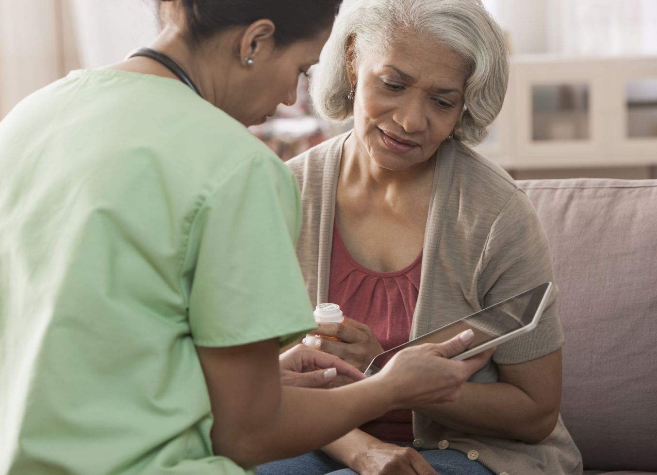 Healthcare provider showing an elderly woman information on an iPad.